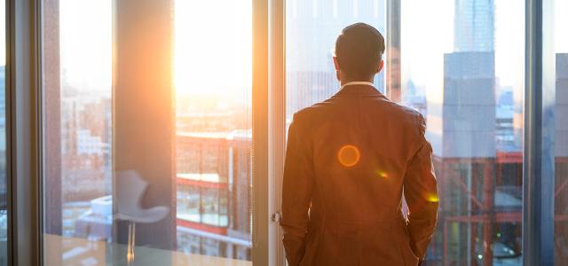 Person looking through a window with a sunset shining on their face